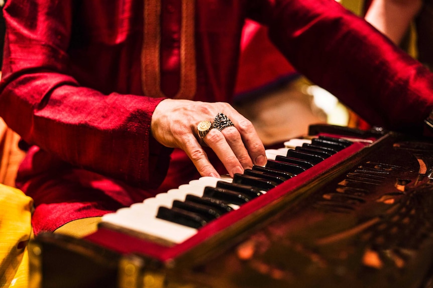 Close up of man playing harmonium for kirtan music session at Govinda's in Sydney.