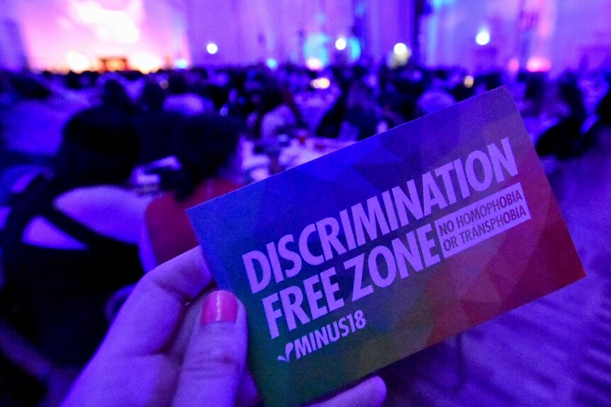 A business card reads 'Discrimination-free zone, no homophobia, no transphobia'.