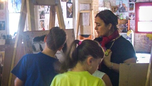 Woman with easel teaching art to young children.