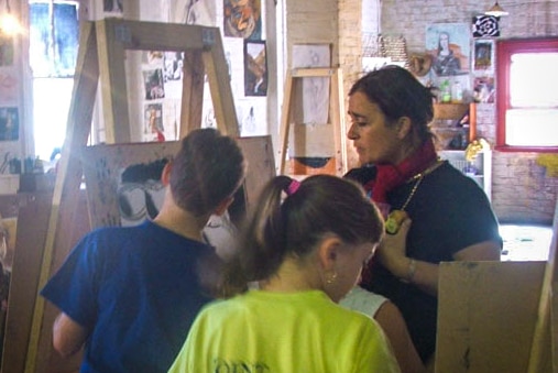Woman with easel teaching art to young children.