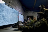 Ukrainian soldiers watch drone feeds from an underground command centre. 