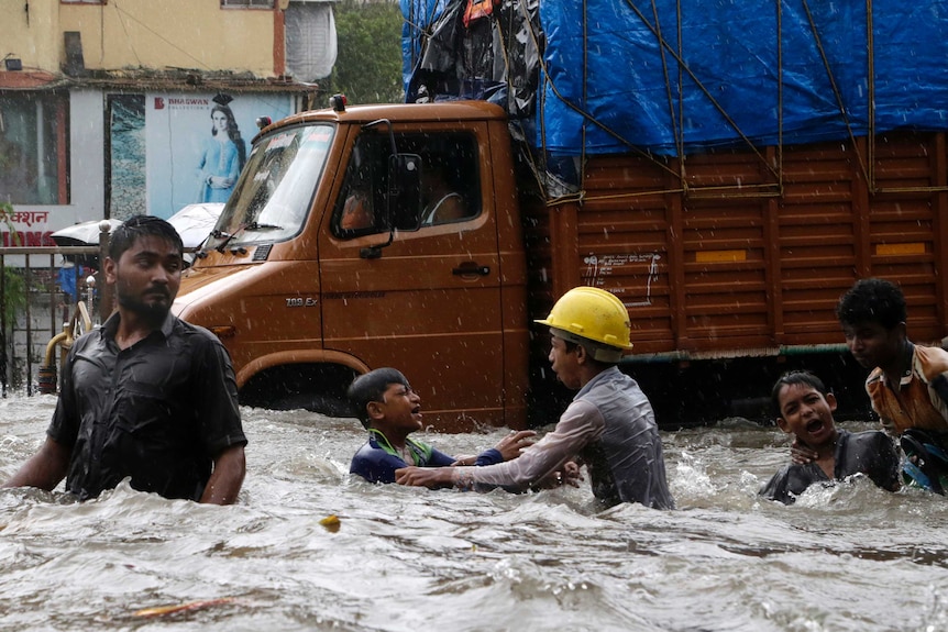 People in waist-deep floodwaters in a Mumbai street.