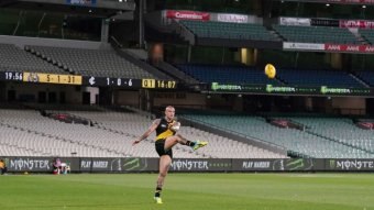 Dustin Martin kicks a ball at an empty MCG.