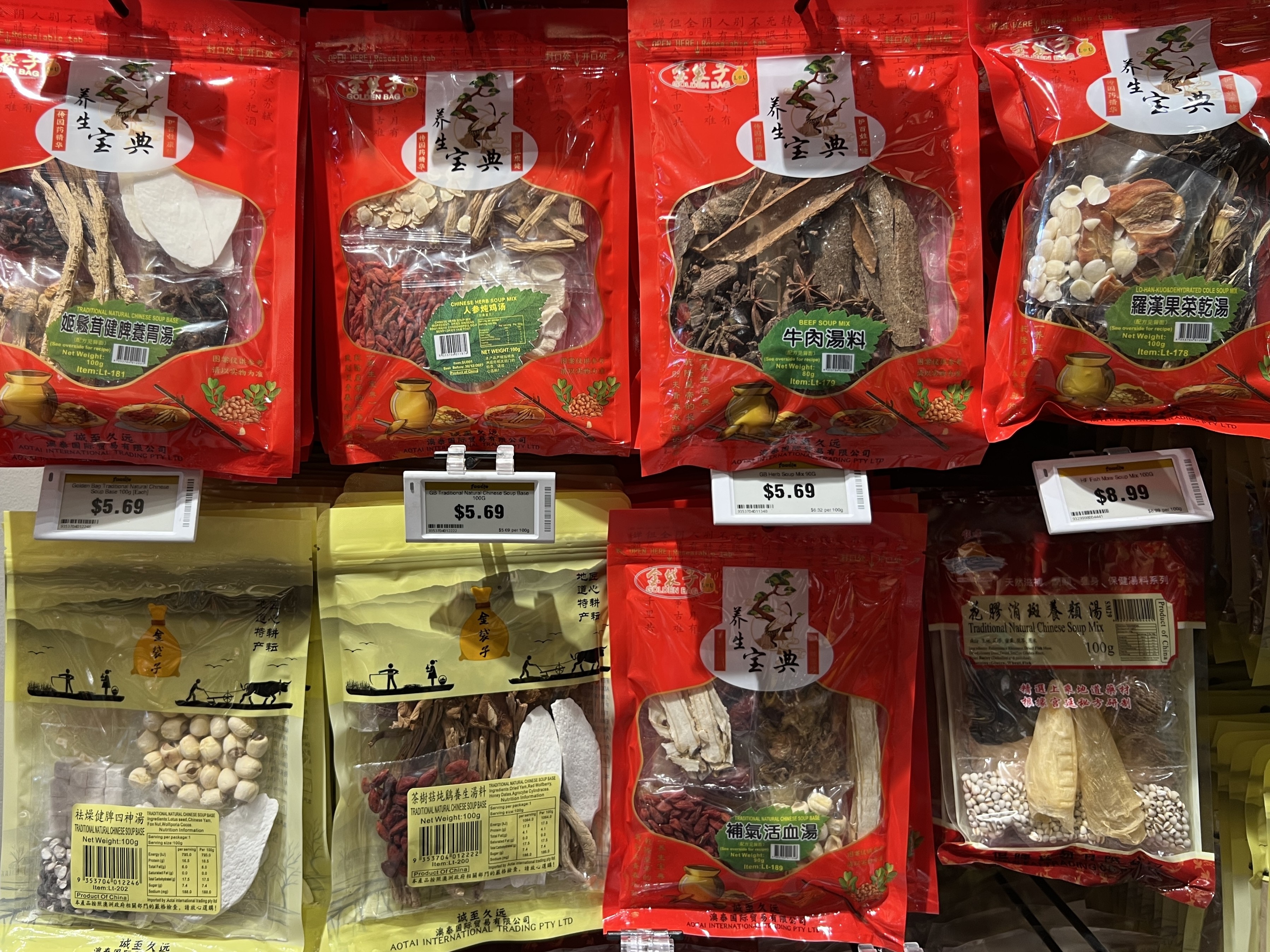 Bolsas de plástico color crema y rojo con combinaciones de hierbas crudas que parecen semillas, corteza y frutos secos en el supermercado