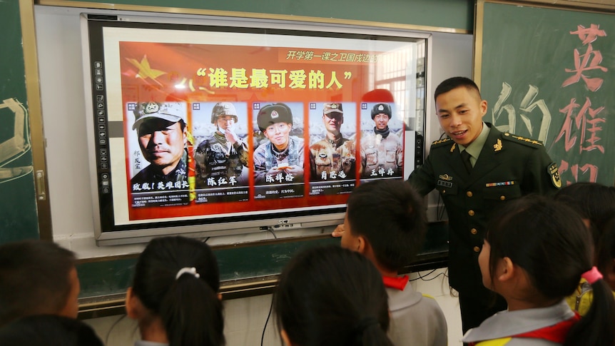 A paramilitary police officer speaks to a group of Chinese primary school students. 