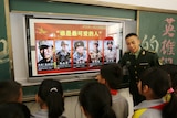 A paramilitary police officer speaks to a group of Chinese primary school students. 