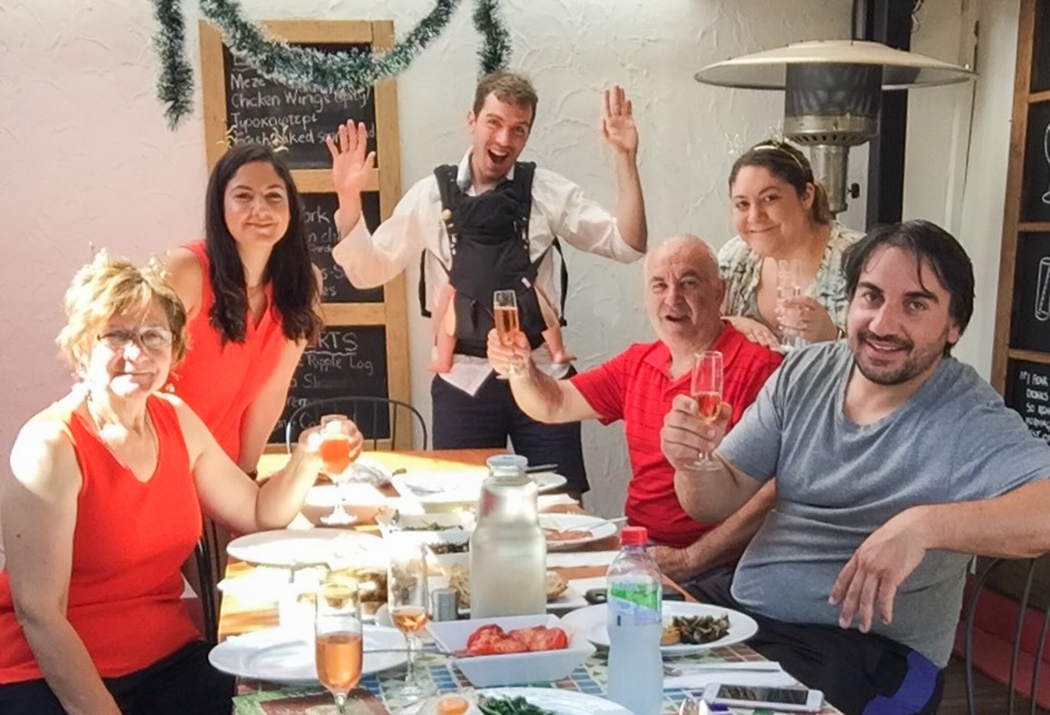 A family of many generations crowds around a table covered in plates of food. 