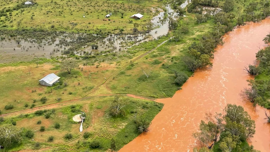 an aerial photo of a brown creek flowing through green pastoral country. 