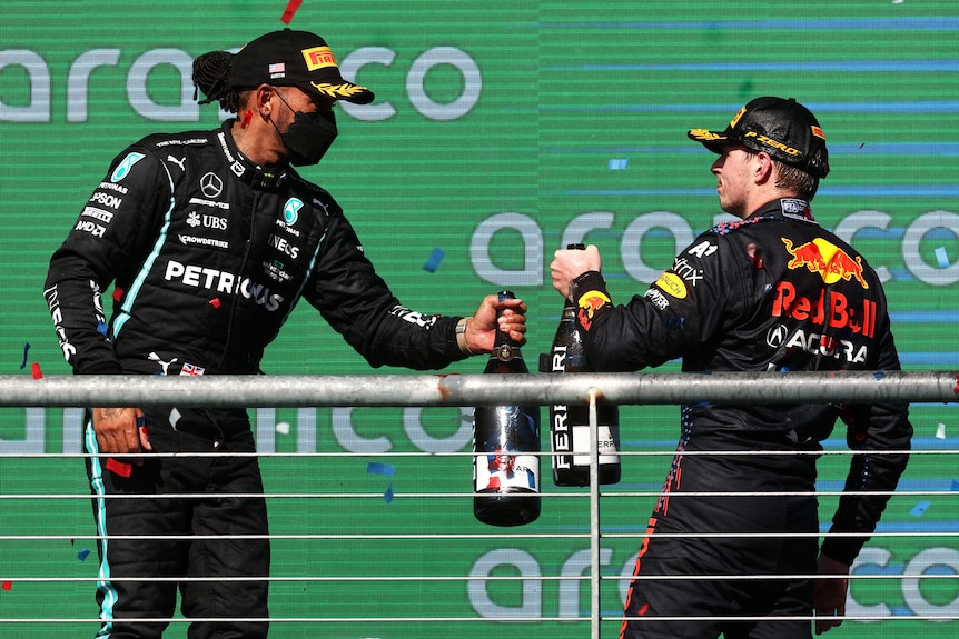 Lewis Hamilton and Max Verstappen cheers with large bottles of champagne on the podium
