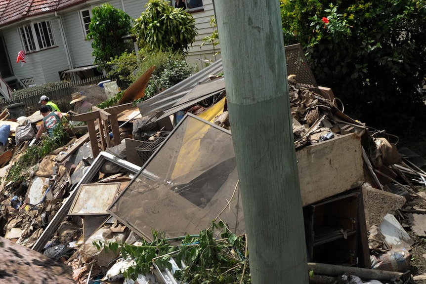 A volunteer throws rubbish into a truck in the flood-hit Brisbane suburb of Graceville