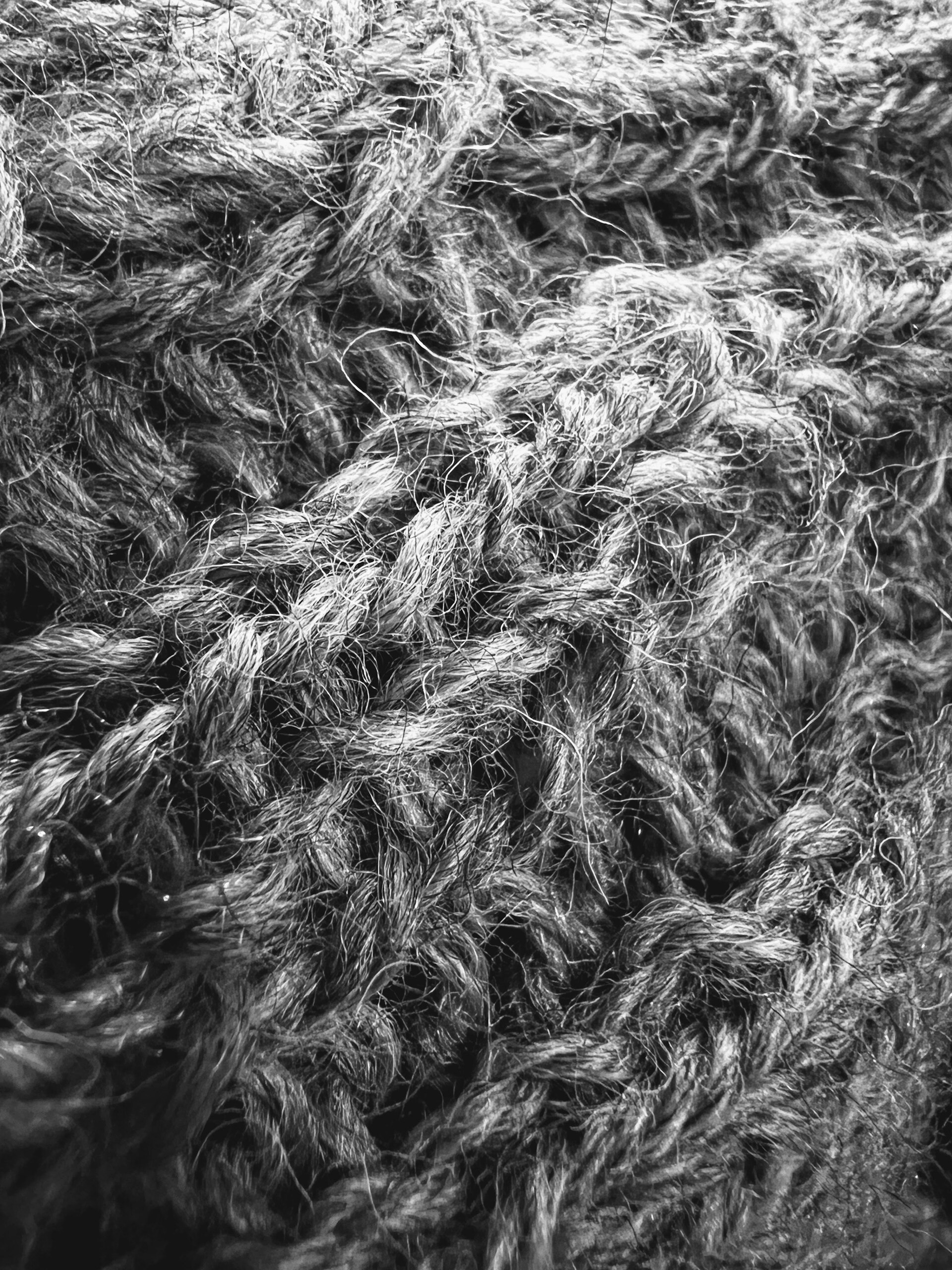 A close up of a thick grey woollen knit, showing the long tendrils of the wool fibres and the gaps between them