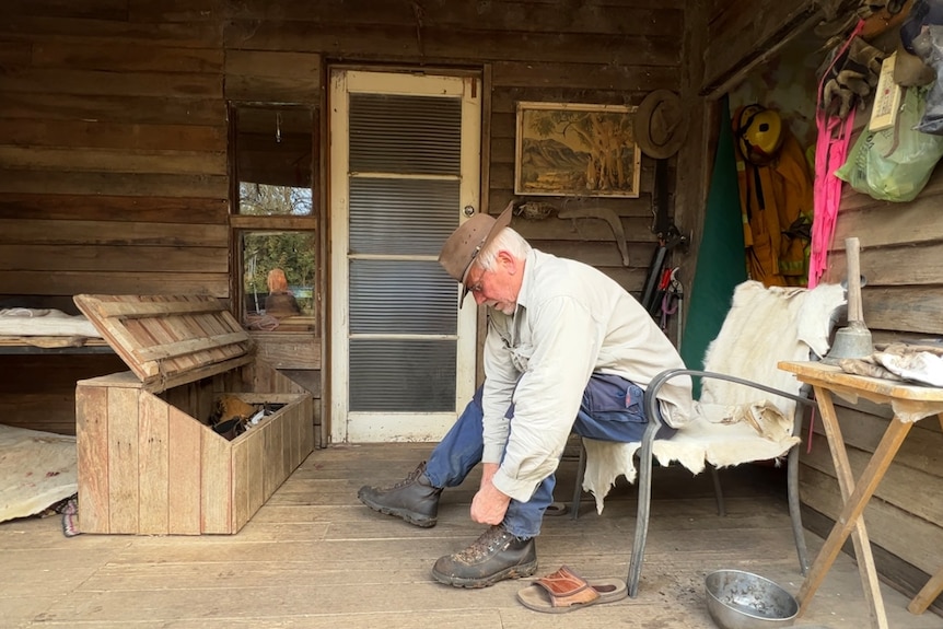 Man sits on wooden porch putting on shoes
