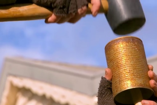 Hammer hitting a rusty can that is on top of a stake being driven into dirt, illustrating our Gardening Australia episode recap.