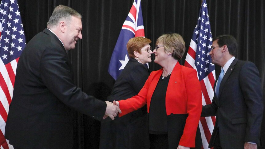 Linda Reynolds and Mike Pompeo shake hands as Marise Payne and Mark Esper shake hands in front of Australian and US flags