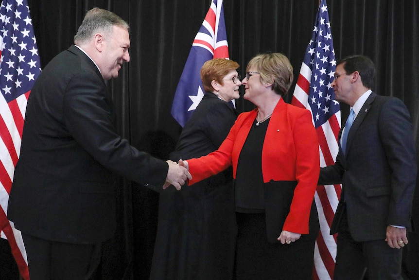 Linda Reynolds and Mike Pompeo shake hands as Marise Payne and Mark Esper shake hands in front of Australian and US flags