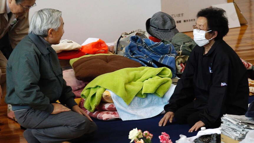 Akihito kneels down to speak to a woman at a Fukushima evacuation centre in 2011