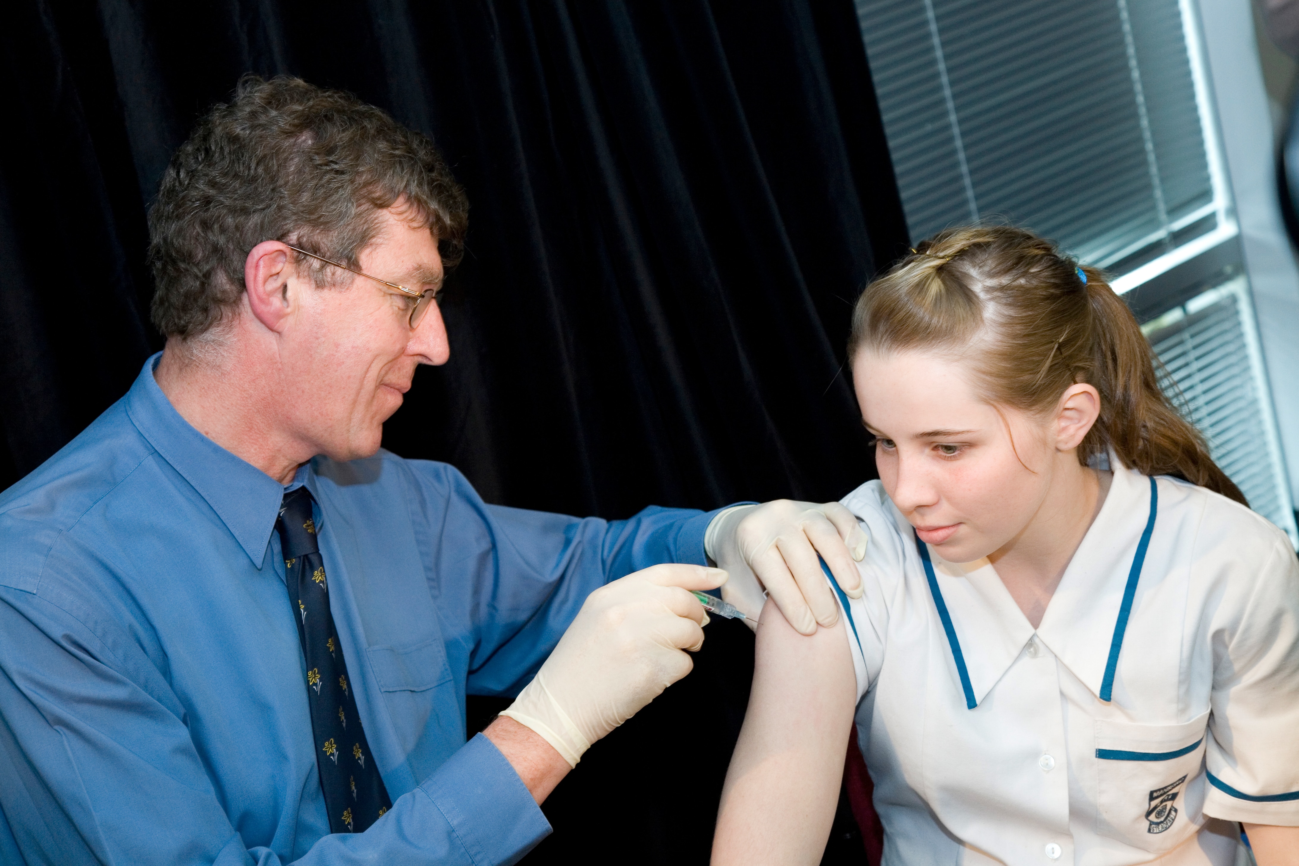 a doctor gives an injection to a young school girl in 2006