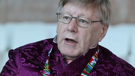 Man wearing purple Chinese tang suit, lanyard and glasses.