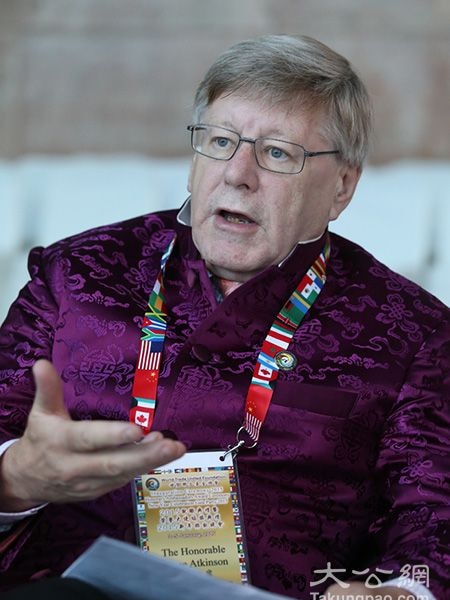 Man wearing purple Chinese tang suit, lanyard and glasses.