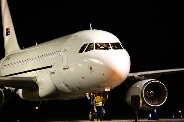 A white passenger plane with the Australian flag on its tail sitting on the tarmac on Christmas Island at night.