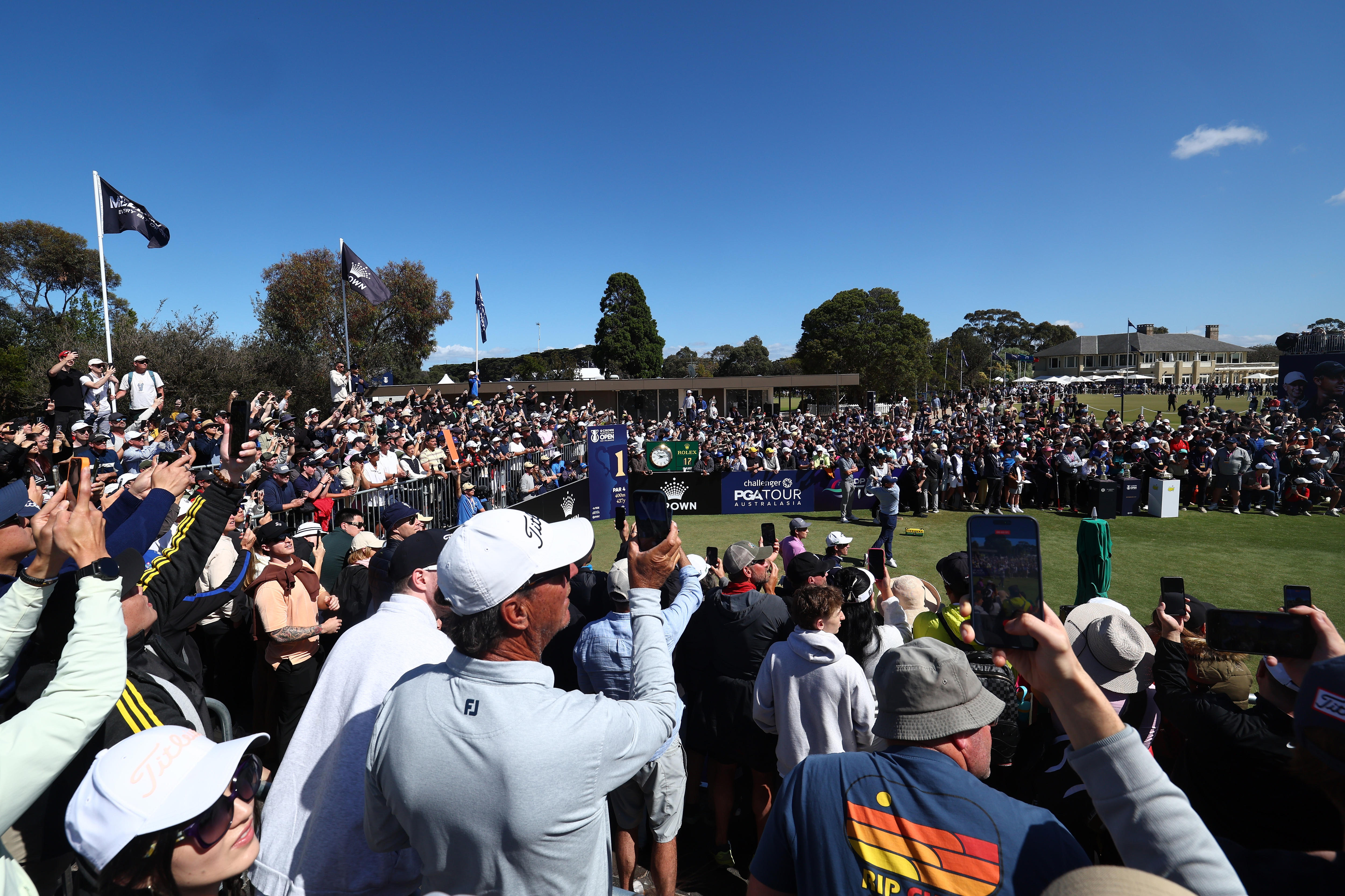 Os espectadores seguram seus telefones assistindo Rory McIlroy jogar o Aberto da Austrália.