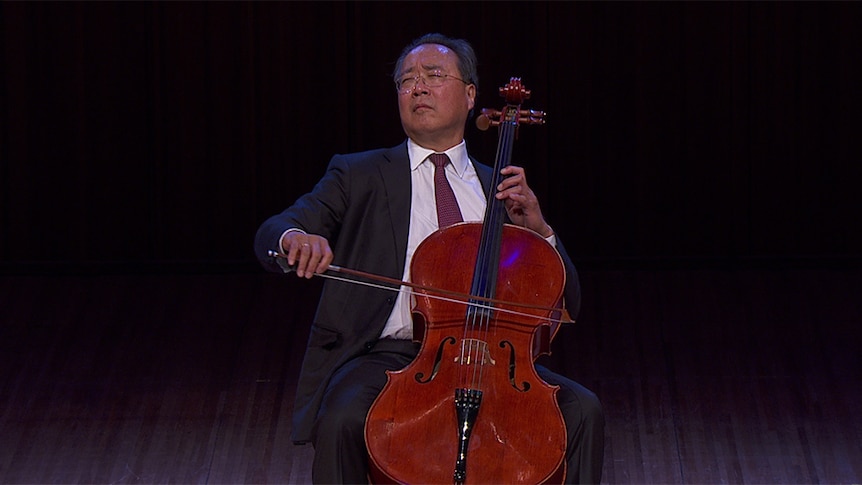 Cellist Yo-Yo Ma plays cello on stage in a black suit. His eyes are closed.