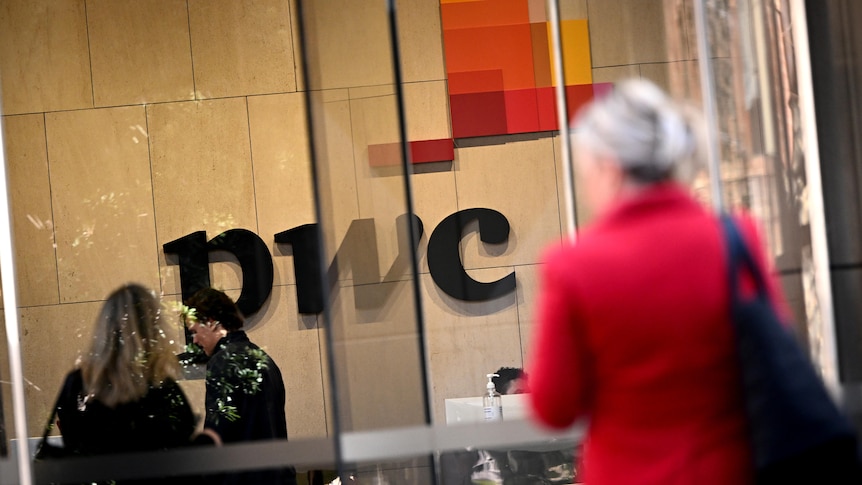 the PWC sign inside its lobby, with a woman in a red jacket walking by
