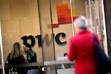 the PWC sign inside its lobby, with a woman in a red jacket walking by