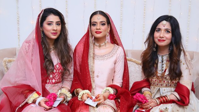 A woman in pink and red bridal attire with her friends