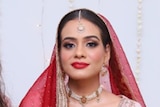 A woman in pink and red bridal attire with her friends
