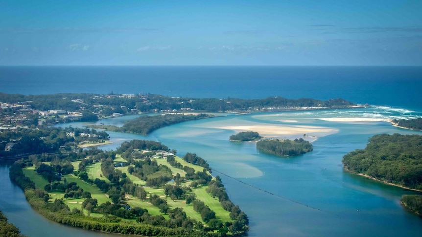 Aerial view of green coastal golf course surrounded by river