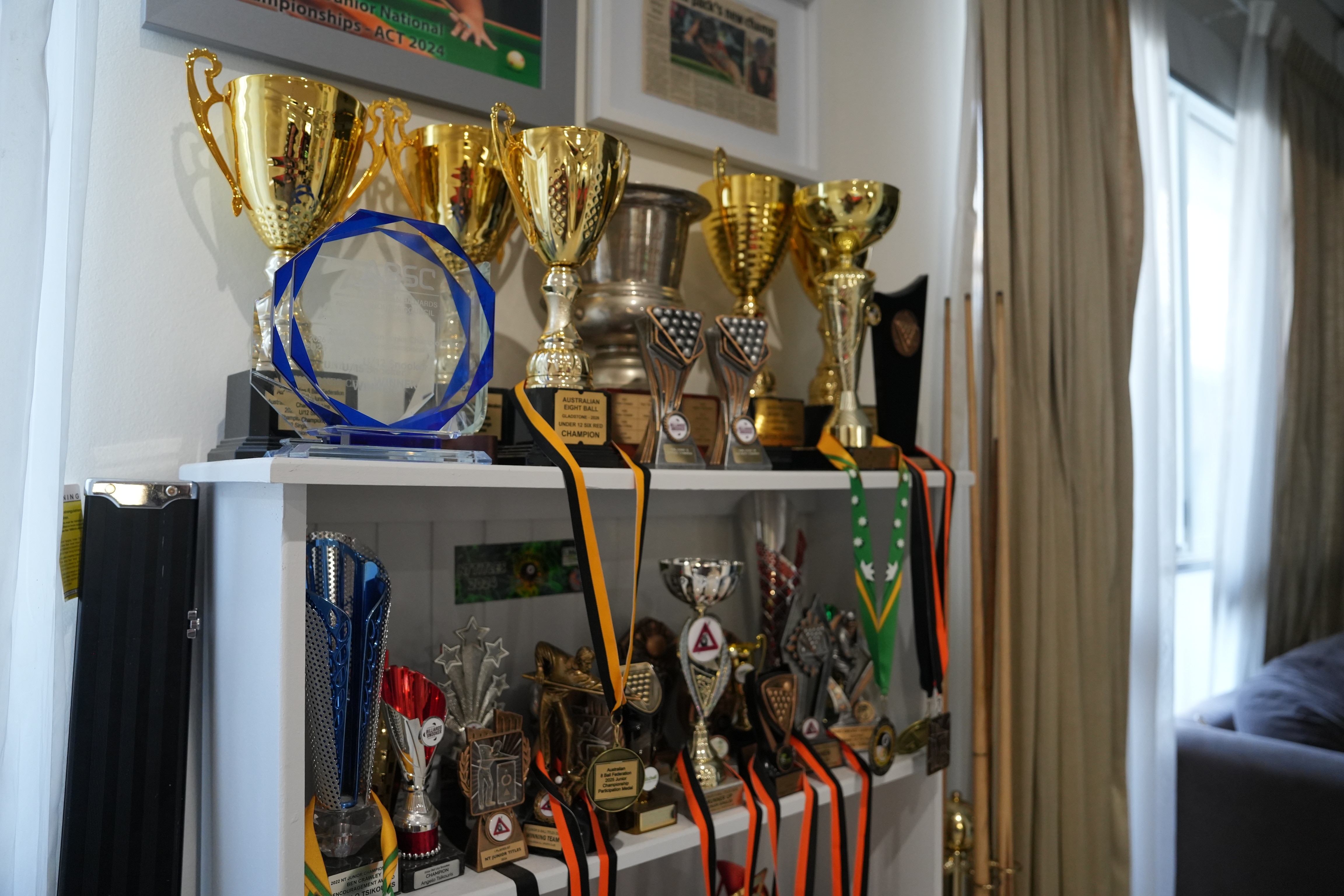 A trophy case full of junior snooker trophies and medals.
