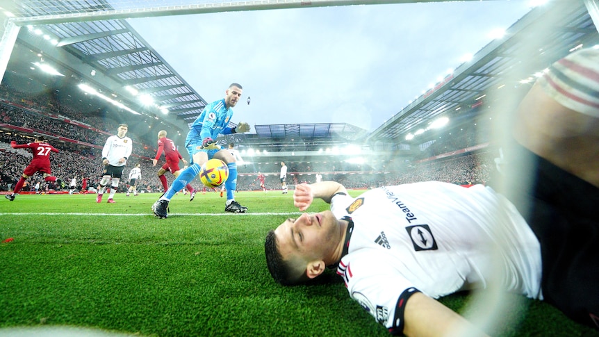 A Manchester United player lies in the goal as goalkeeper David de Gea tries to get the ball after another Liverpool goal.