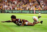 A Brisbane Broncos player lies in the in-goal, acting as if he is swimming after a try.