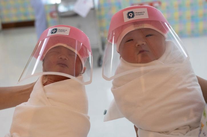 Two babies with plastic shields over their faces