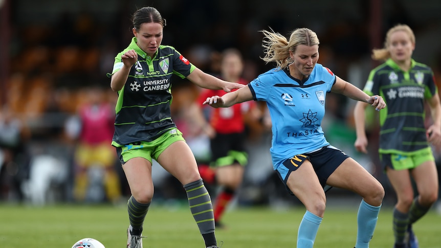 Grace Maher and Ally Green run alongside each other, chasing the soccer ball