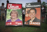 Two corflute signs side-by-side on the ground, showing the faces of NT politicians Eva Lawler and Lia Finocchiaro.