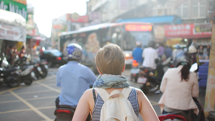 Photo of a woman backpacking in a busy city. 
