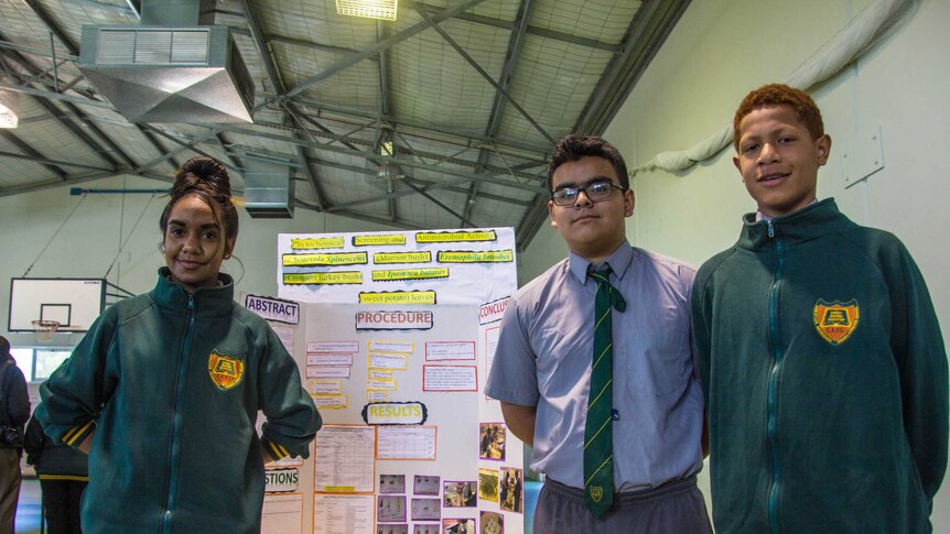Coolgardie school students stand next to a research project on show at a science fair.