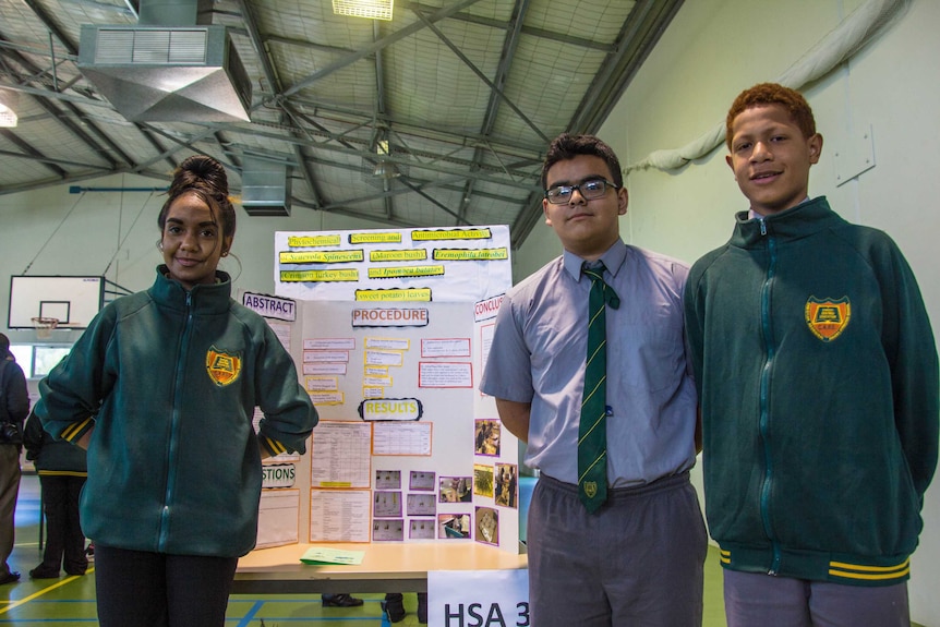 Coolgardie school students stand next to a research project on show at a science fair.