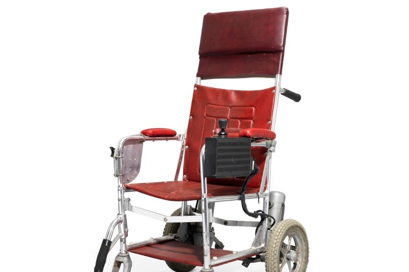 A red wheelchair, which is fitted with a joystick and a motor.