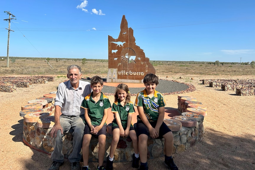 Grandfather and three kids in front of 'centre of qld' sign