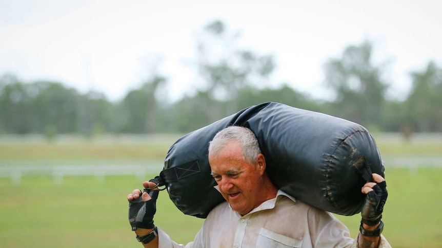 Dave Holleran carries a heavy black leather sandbag over his shoulders.