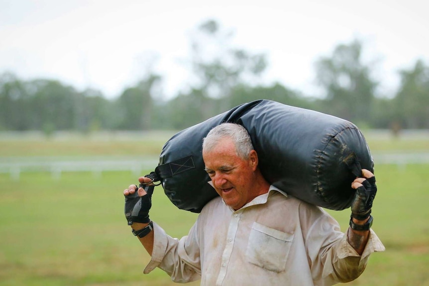 Dave Holleran carries a heavy black leather sandbag over his shoulders.
