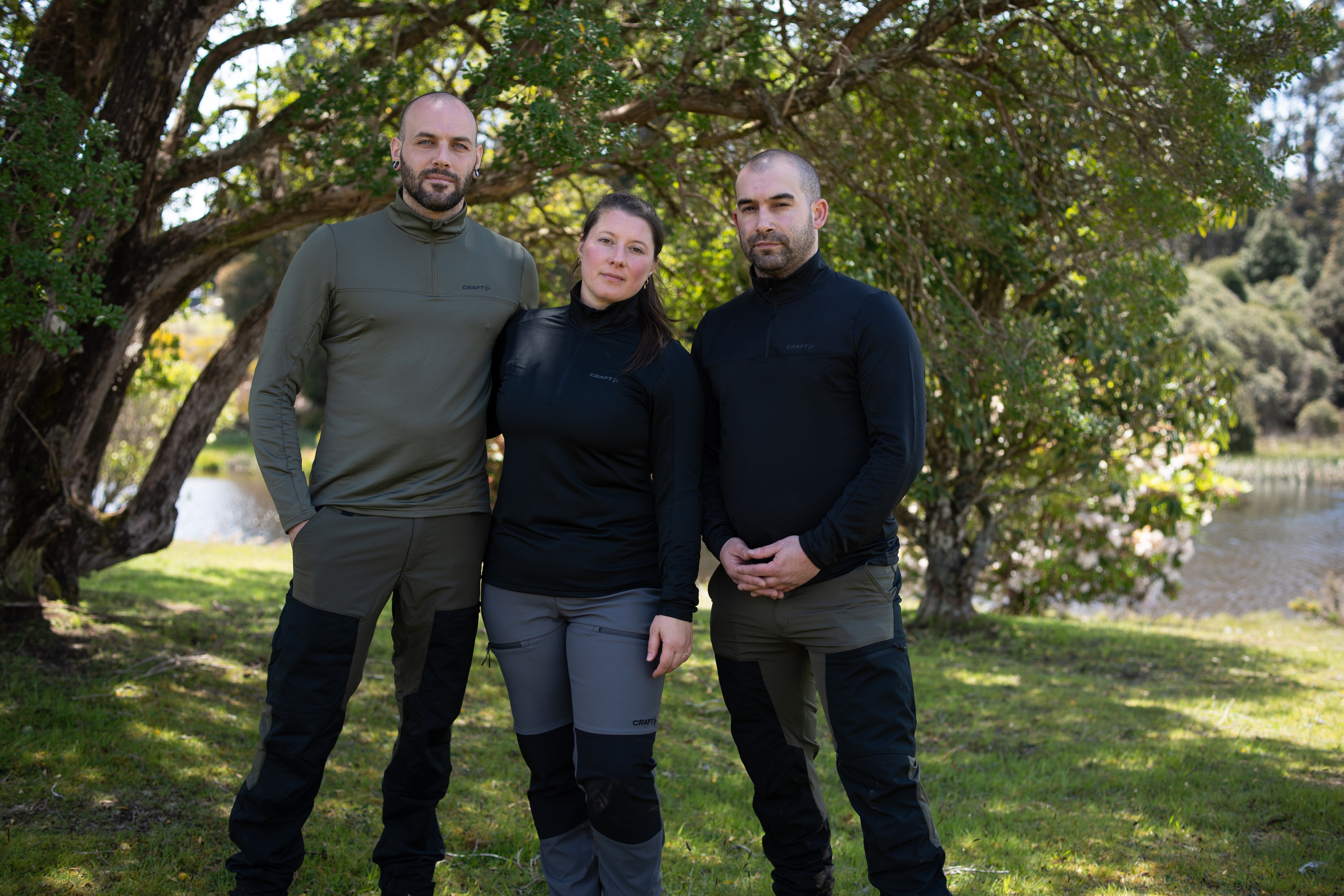 Três pessoas ficam próximas uma da outra para fazer um retrato