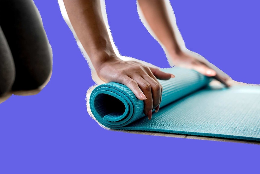 Woman rolling out a green yoga mat