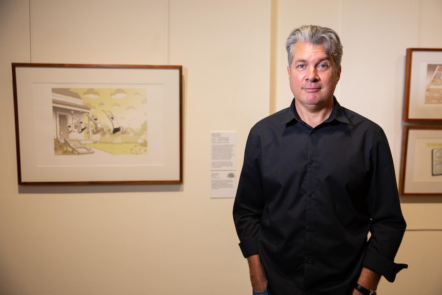 A man with grey hair wearing a black shirt smiles for the camera