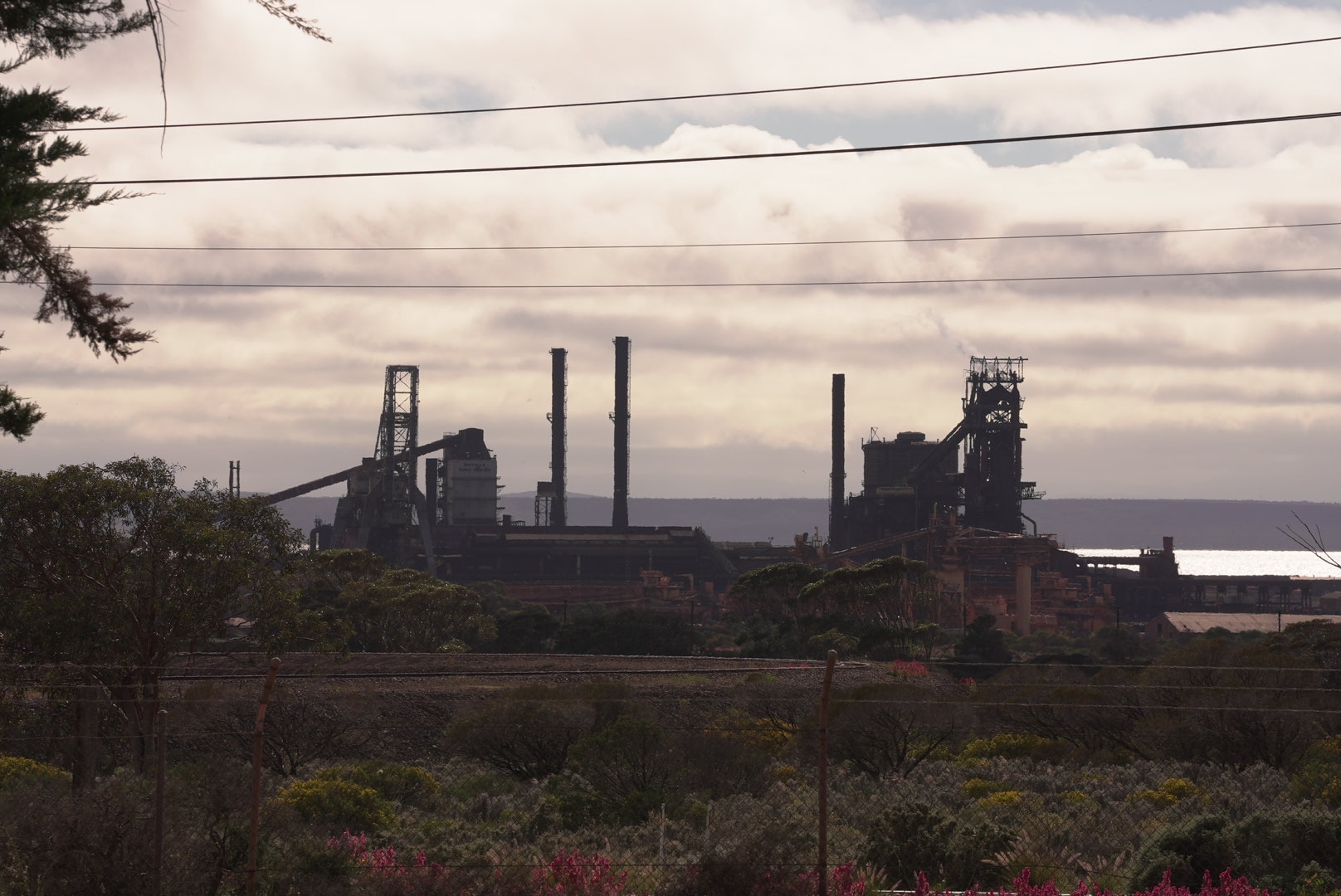 A photo of the Whyalla blast furnace facility, consisting of several buildings, railyards, buildings, towers and chimneys
