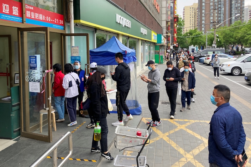 Long line of people queueing outside a supermarket.