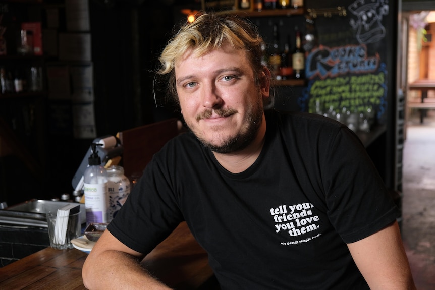 A young man sitting at a bar looking at the camera.